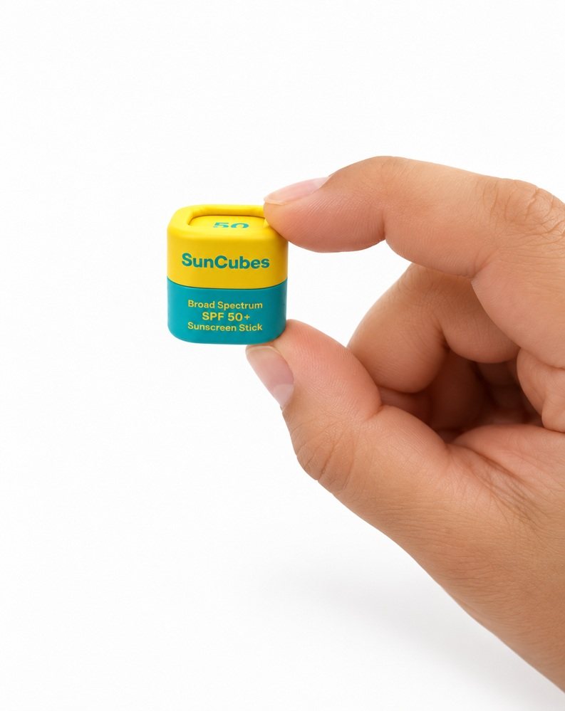 A hand holding the SunCubes SPF 50+ sunscreen cube between two fingers, showing how small it is.